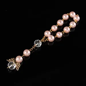 Detail of beaded keychain with pink pearls, golden angel wings, and crystal drop pendant