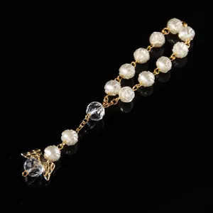 Detailed macro view of religious rosary bracelet with white roses and golden angel charm