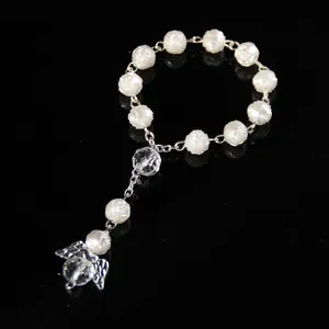 Detail of white resin rose beads and crystal angel wing pendant on religious rosary