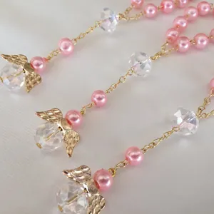 Detail of pink pearls and crystal beads with a golden angel wing charm on a chain