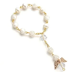 Close-up of white rose-carved beads with golden angel wing and crystal pendants