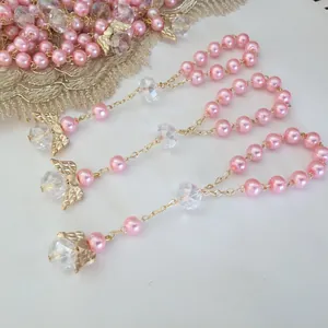 Pink pearl and crystal rosary bracelet with golden angel wings charms on white background