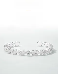 Macro detail of leaf-shaped silver bangle with hand-brushed texture and cubic zirconia