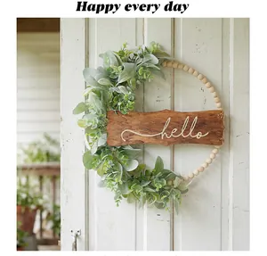 Détail d'un panneau hello en bois sur une couronne de perles d'eucalyptus sur une porte blanche
