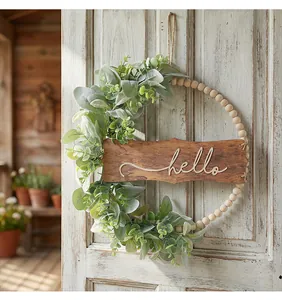 Détail d'une couronne en bois avec feuilles vertes et panneau hello sur une porte