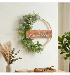 Détail de la couronne en perles de bois avec feuilles d'eucalyptus et signe Hello