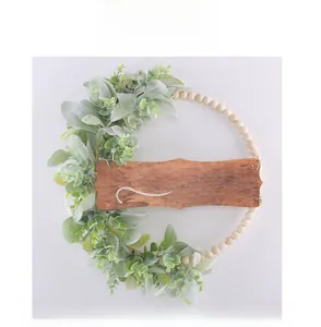 Détail d'une couronne en perles de bois avec feuilles d'eucalyptus et plaque 'hello'