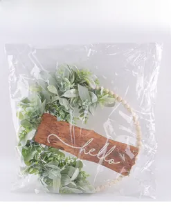Gros plan de la couronne décorative Hello en perles de bois dans son emballage plastique