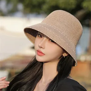 Detail of light coffee knitted bucket hat with white decorative stitching on a model