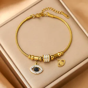 Macro detail of gold stainless steel snake chain bracelet with crystal evil eye charms