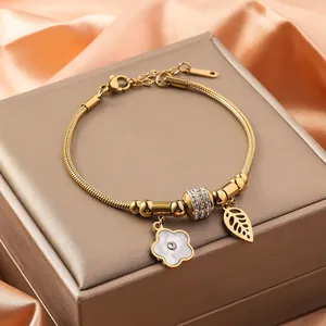 Detail view of 18K gold plated clover charm bracelet with sparkling crystals on satin