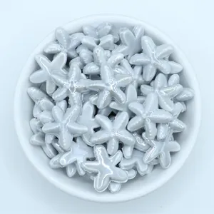 Close-up of glazed light blue starfish ceramic beads for DIY jewelry making in a white bowl