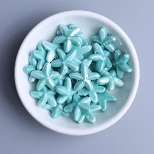 Macro detail of glossy blue starfish ceramic beads for DIY jewelry making in a white bowl