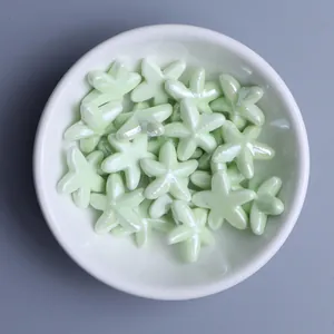 Close-up of pearlized light green starfish ceramic beads in a white bowl for DIY jewelry