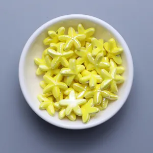Close-up of glazed yellow starfish ceramic beads for DIY jewelry in a white bowl