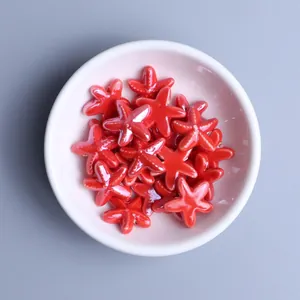 Macro view of bright red starfish ceramic beads for DIY jewelry in a white bowl