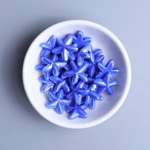 Close-up of blue glazed starfish ceramic beads for DIY jewelry making in a white bowl