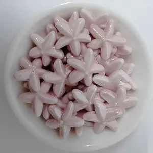 Close-up of pink glazed starfish ceramic beads for DIY jewelry making in a white bowl
