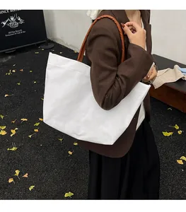 Close-up of white canvas tote bag with brown handles and a stylish minimalist design