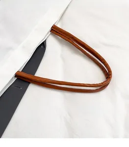 Detail of white canvas tote featuring durable brown PU leather round handles and gray straps