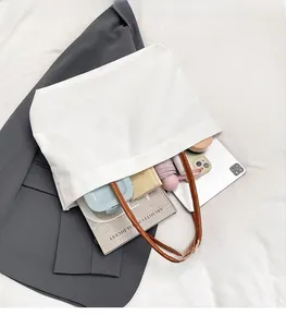Detail of white canvas tote bag showing large capacity for iPad, umbrella and essentials