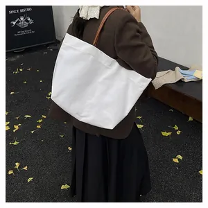 Outdoor shot of a large white canvas tote bag with brown leather straps on a model