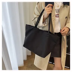 Detailed view of the black canvas tote bag showing large capacity and long shoulder straps