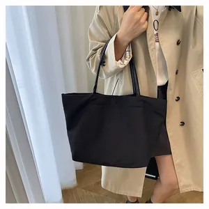 Minimalist black canvas tote bag styled with a beige trench coat for a casual daily look