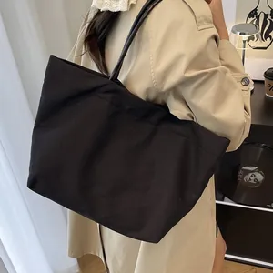 Minimalist large black canvas tote bag with slim shoulder straps for daily commuting