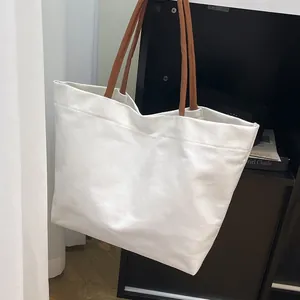 Minimalist white canvas tote bag with brown leather straps for daily commute shopping