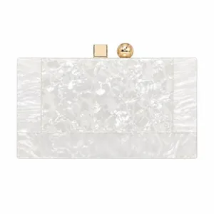 Macro view of white marble acrylic evening clutch with gold geometric metal clasp