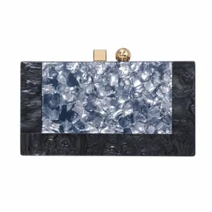 Detail of evening clutch featuring marble texture acrylic and golden geometric clasp