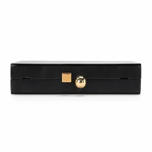 Detail of black acrylic evening clutch with glossy finish and gold geometric metal clasp