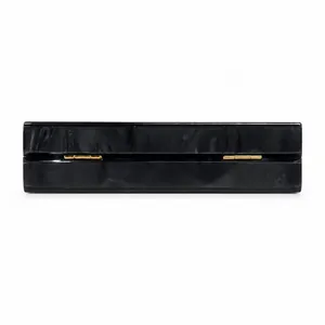 Close-up of golden hinges on black marble acrylic evening clutch bag with chain strap