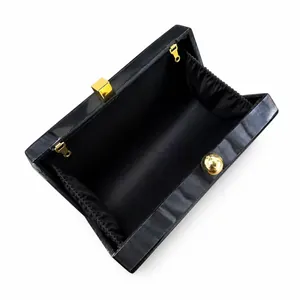 Detail view of acrylic evening bag with marble texture and gold hardware clasp