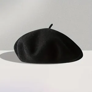 Close-up of black wool beret showing fine felt texture and classic top stem detail