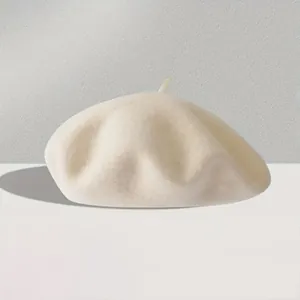 Close-up of off-white wool beret showing thick textured material and top stalk detail