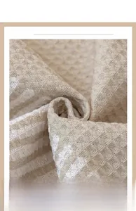 Vue macro détaillée de la texture en coton gaufré crème montrant les motifs entrelacés