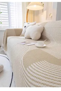 Détail d'un jeté de canapé en maille gaufrée avec vagues beiges et bordures à franges