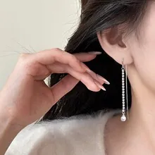 Nahaufnahme eleganter Blatt-Ohrring mit glänzenden Kristallen und einer weißen Perle