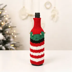 Macro shot of knitted Christmas wine bottle cover with red stripes and golden bell