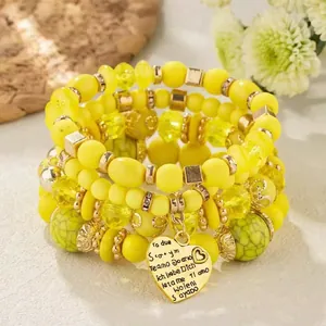Detail of yellow multilayer beaded bracelet with heart pendant engraved with I Love You