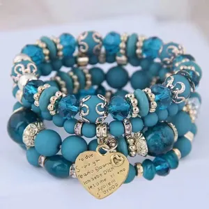 Detail of bohemian multilayer blue crystal beaded bracelet set with golden heart pendant