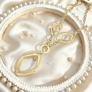 Close-up of golden geometric double diamond pendant with polished and matte textures
