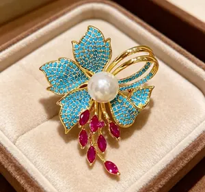 Macro di una spilla vintage francese con perla, petali turchesi e gemme rosse