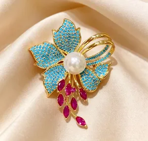 Dettaglio di una spilla a iris vintage con perline turchesi, perla e nappe di rubino