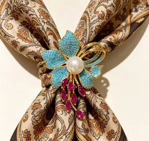 Dettaglio della spilla a iris vintage con turchese blu, perla e pietre rosse