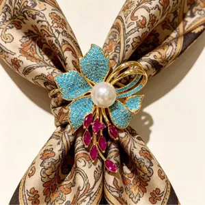 Spilla iris vintage con petali turchesi e perla centrale su foulard di seta