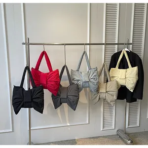 Close-up of bow-shaped quilted tote bags displayed in multiple colors on a metal rack