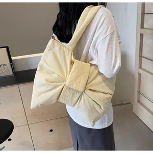 Detail of light yellow bow tote bag showing soft quilted texture and wide shoulder strap